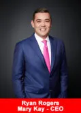 Ryan Rogers, CEO of Mary Kay, in a navy blue suit and pink tie, standing in front of a black background.
